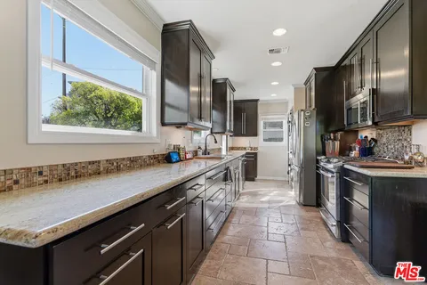 a kitchen with stainless steel appliances granite countertop a sink counter space cabinets and a large window