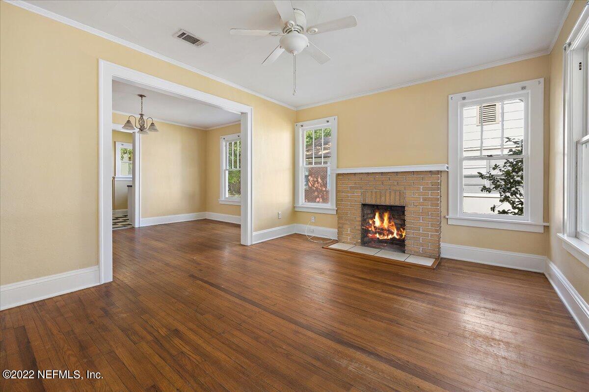 352 West 68th Street Jacksonville, FL 32208 - Photo 5 of 11 an empty room with wooden floor fireplace and windows
