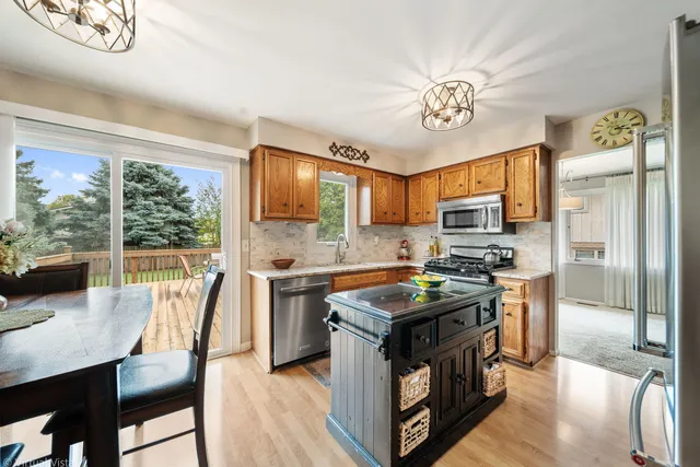 a kitchen with stainless steel appliances granite countertop a stove a refrigerator a sink dishwasher a dining table and chairs with wooden floor