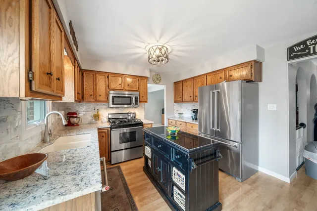 a kitchen with stainless steel appliances granite countertop a refrigerator a stove and a sink