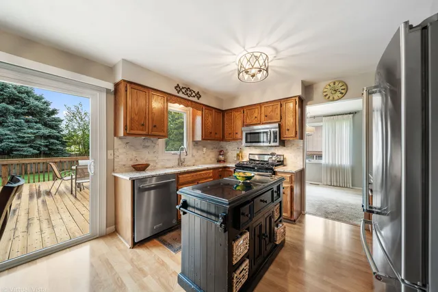 a kitchen with stainless steel appliances granite countertop a stove top oven a sink a refrigerator white cabinets and wooden floor