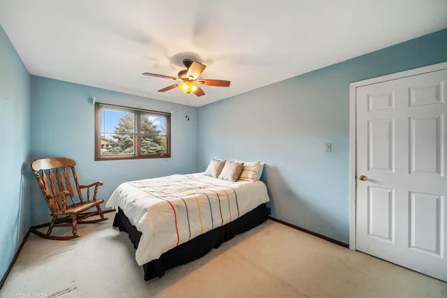 a bedroom with a bed a chair and painting on the wall