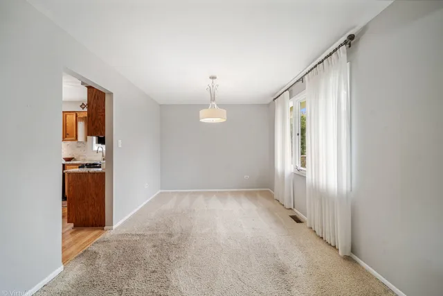an empty room with kitchen view and a window