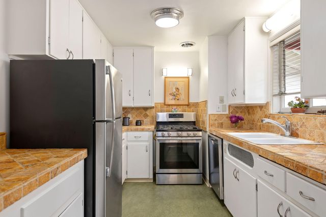 a kitchen with stainless steel appliances granite countertop a refrigerator sink and stove