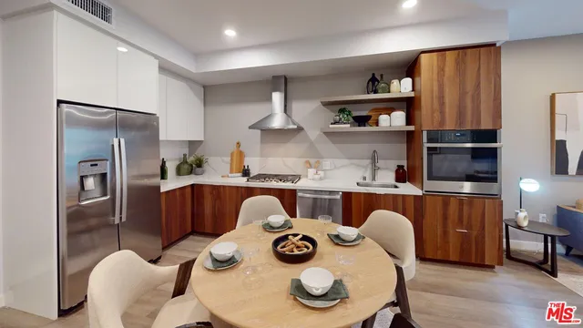 a kitchen with stainless steel appliances granite countertop a table chairs and a refrigerator