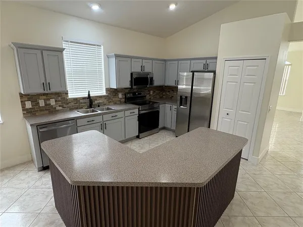 a kitchen with stainless steel appliances granite countertop a stove a sink a microwave a refrigerator and cabinets