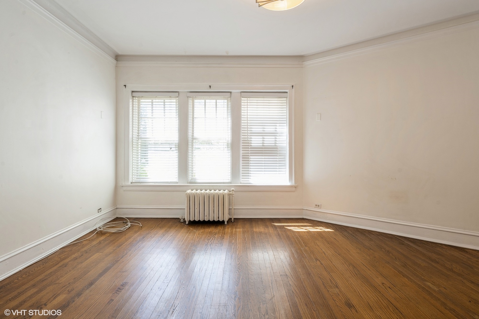 538 West Brompton Avenue, Unit 1W Chicago, IL 60657 - Photo 6 of 16 an empty room with wooden floor and windows with curtains