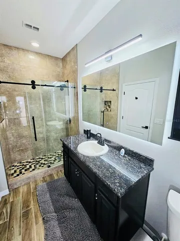 a bathroom with a granite countertop sink a toilet and shower