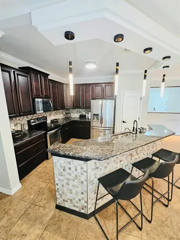 a kitchen with stainless steel appliances granite countertop a stove top oven a sink a dining table and chairs with wooden floor