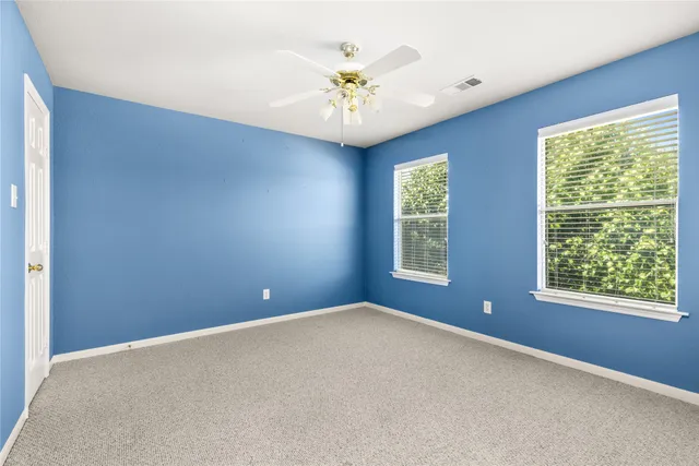 an empty room with windows and chandelier fan