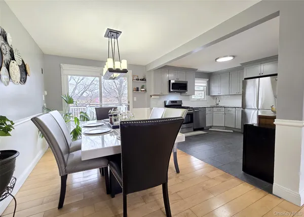 a dining room with kitchen island stainless steel appliances furniture a window and kitchen view