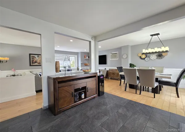 a view of dining room and livingroom with furniture wooden floor a rug a painting and a chandelier