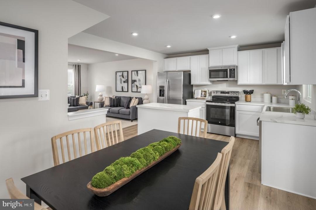 1180 West Walnut Road, Unit 9 Vineland, NJ 08360 - Photo 4 of 17 a view of a kitchen with kitchen island stainless steel appliances wooden floor dining table and chairs