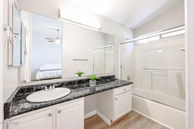 a bathroom with a granite countertop sink mirror and a bathtub