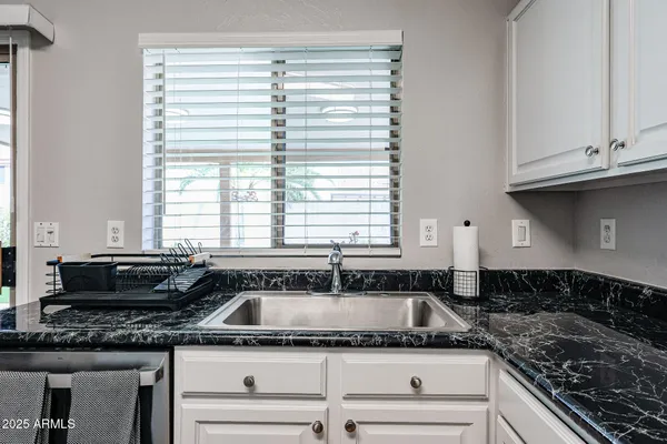 a kitchen with granite countertop a sink and a white wooden cabinets