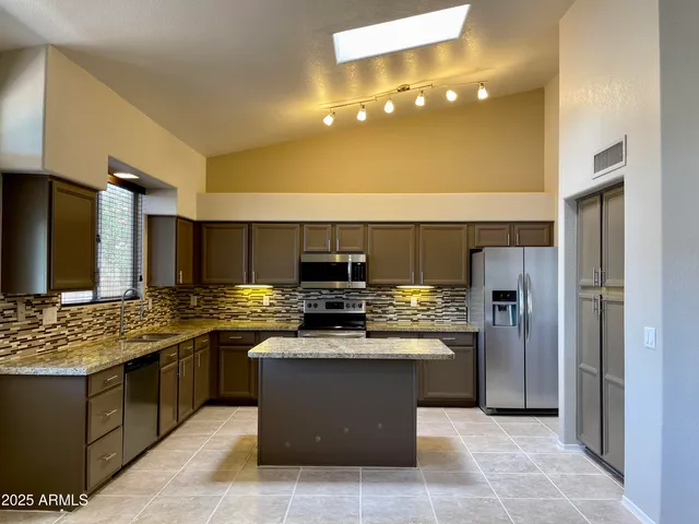 a kitchen with stainless steel appliances granite countertop a sink stove and refrigerator