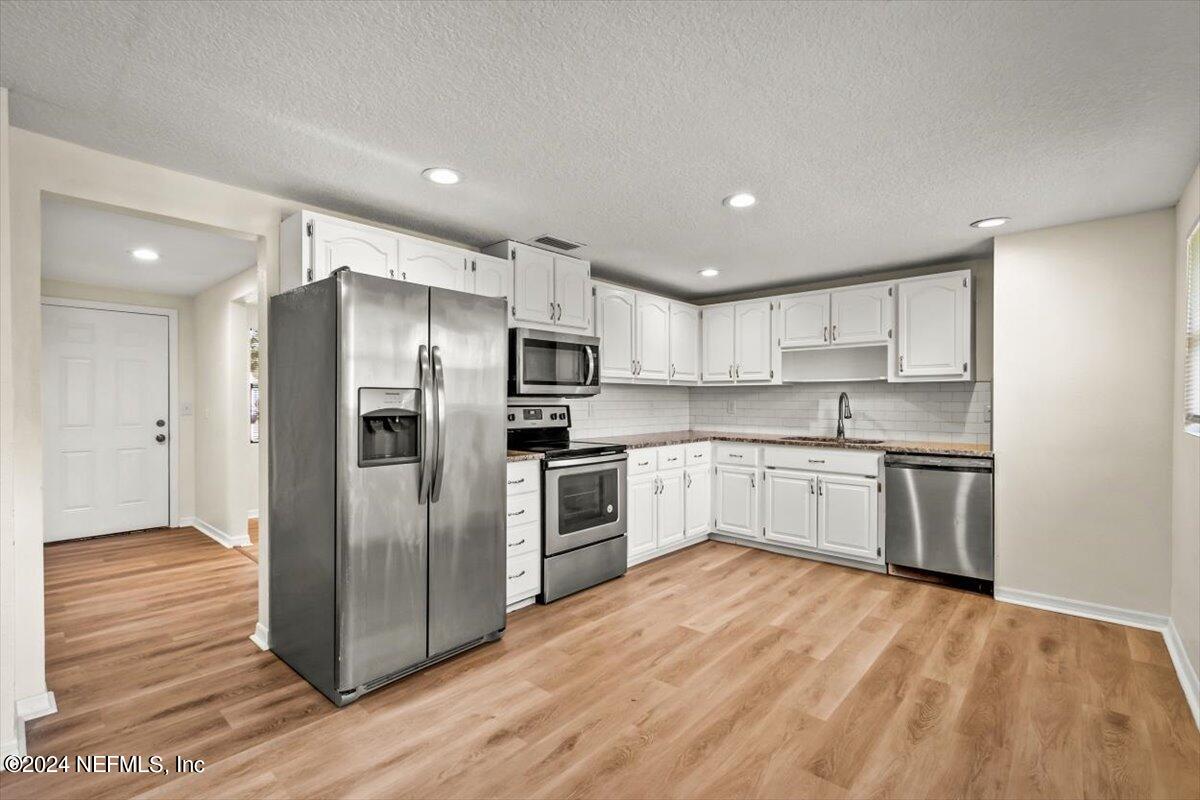 8264 Devoe Street Jacksonville, FL 32220 - Photo 8 of 24 a kitchen with stainless steel appliances a refrigerator sink and white cabinets