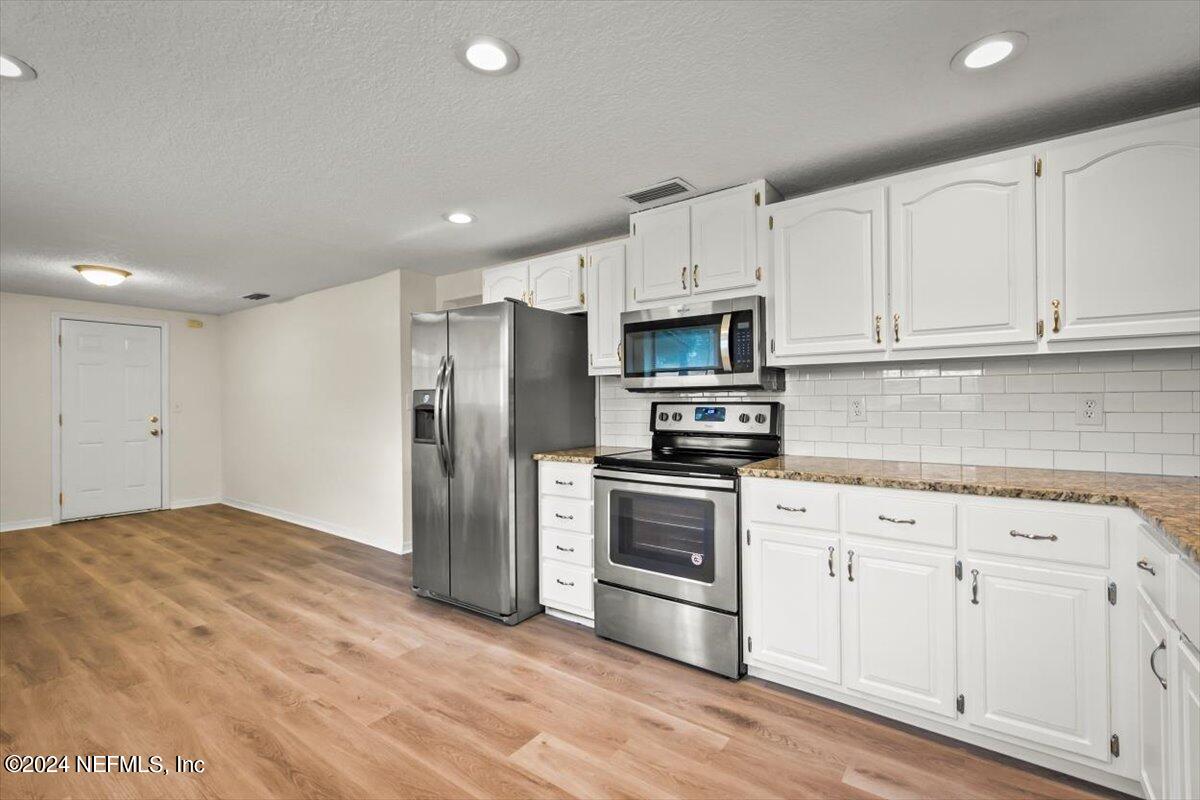 8264 Devoe Street Jacksonville, FL 32220 - Photo 9 of 24 a kitchen with cabinets stainless steel appliances and wooden floor
