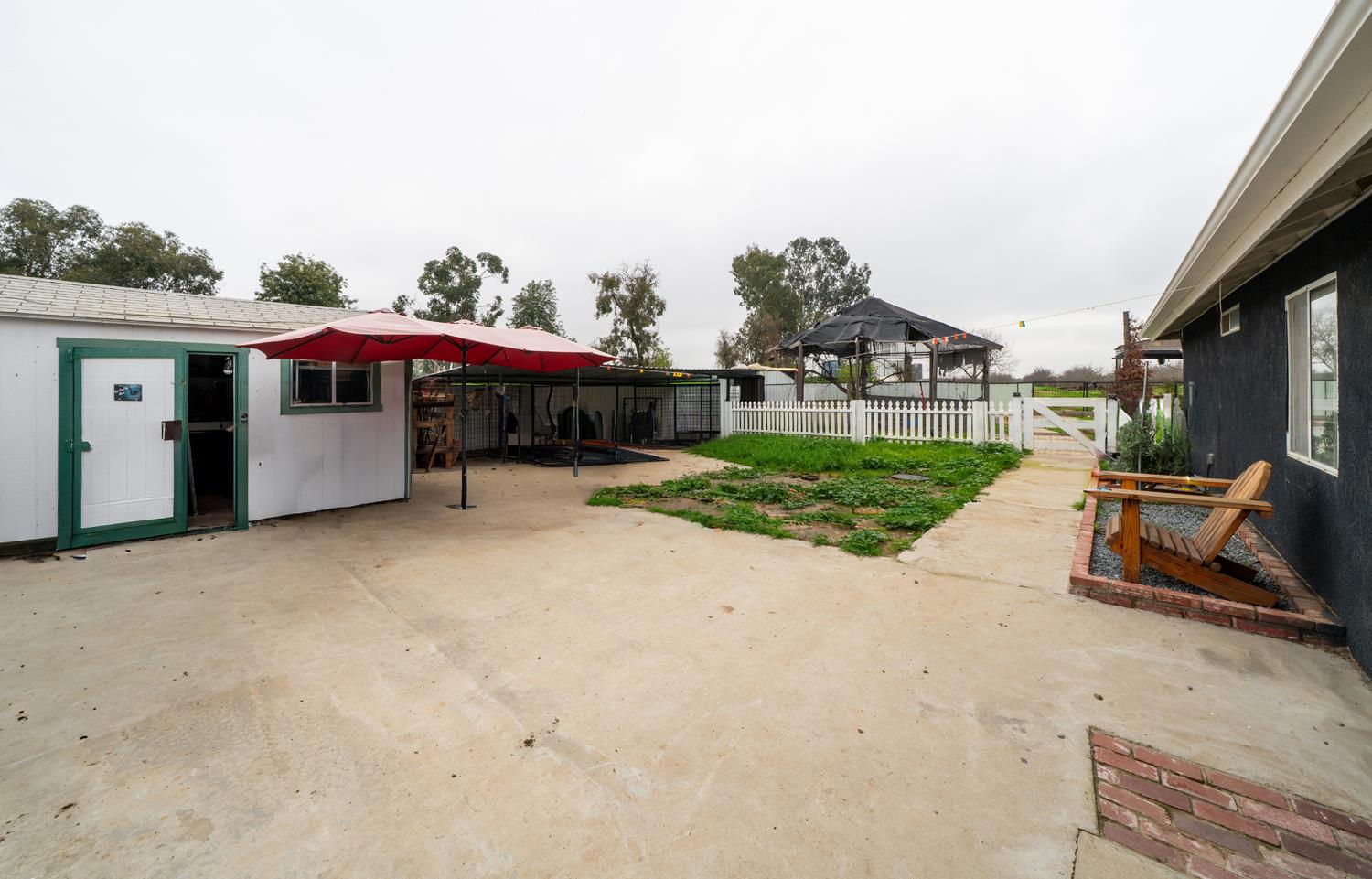 31144 James Avenue Madera, CA 93636 - Photo 41 of 45 a view of a white house with a yard and table and chairs under an umbrella