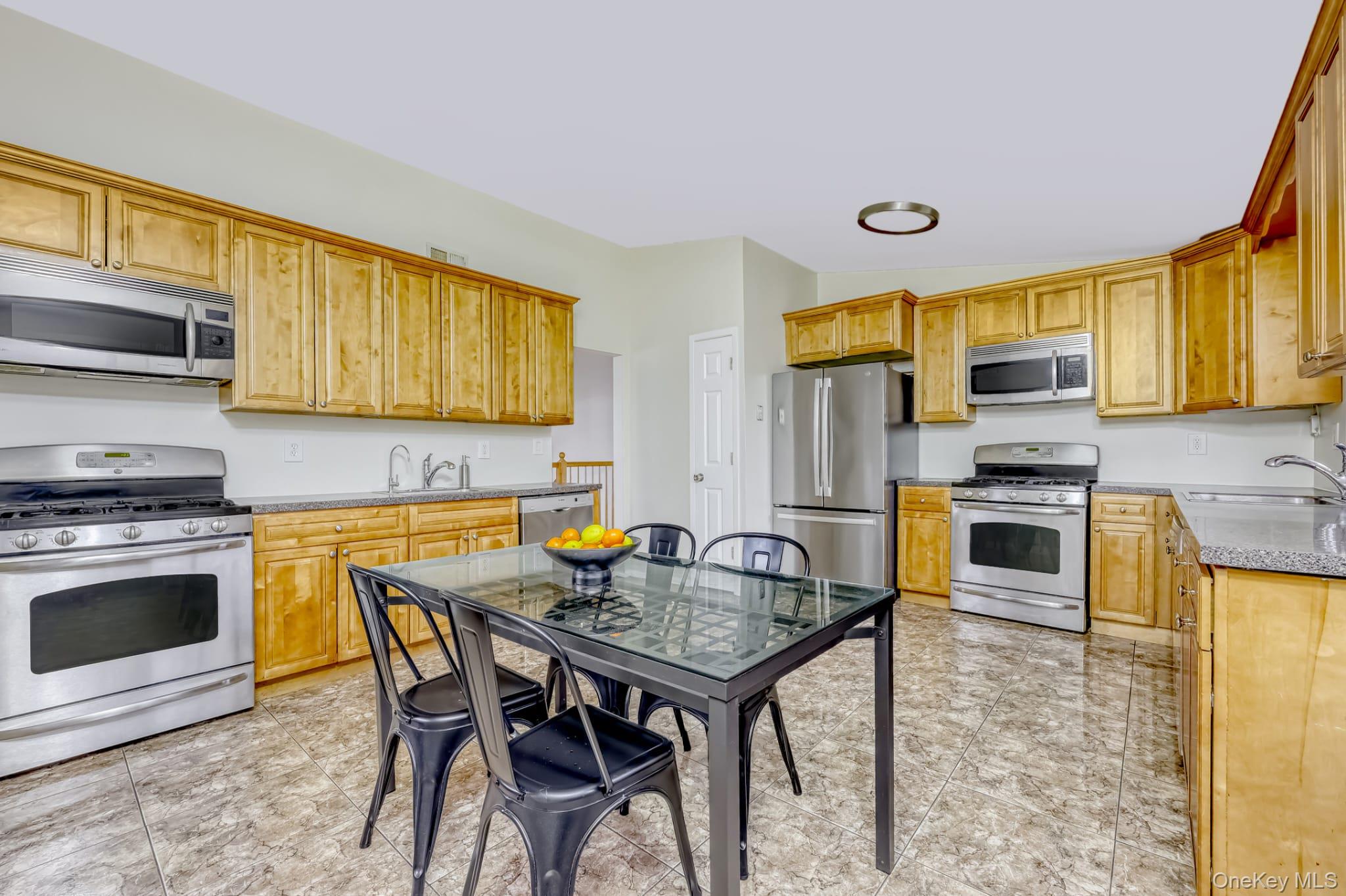 12 Woodwind Lane Spring Valley, NY 10977 - Photo 7 of 27 a kitchen with stainless steel appliances kitchen island granite countertop a stove top oven a sink a dining table and chairs