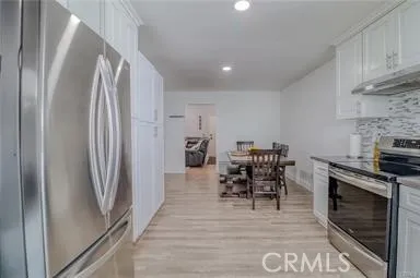a kitchen with stainless steel appliances granite countertop a refrigerator stove and white cabinets