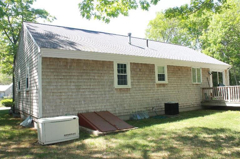 1344 Shootflying Hill Road Centerville, MA 02632 - Photo 17 of 18 a brick house with a large window and yard