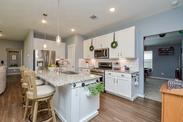 a kitchen with stainless steel appliances granite countertop a sink a stove and microwave