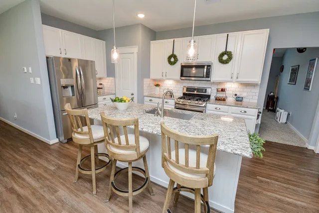 a kitchen with granite countertop a stove a sink a dining table and chairs