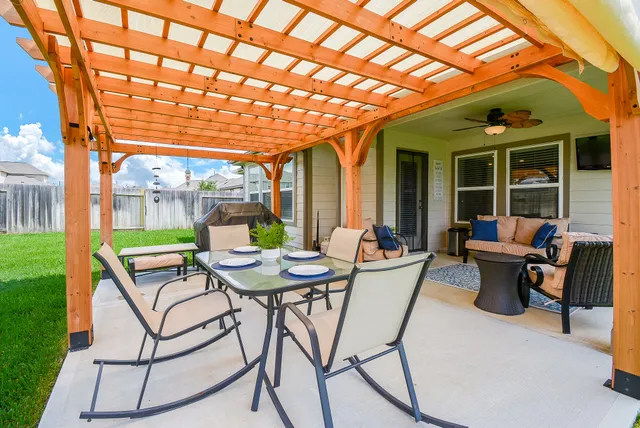 a view of a patio with a table and chairs under an umbrella with a barbeque