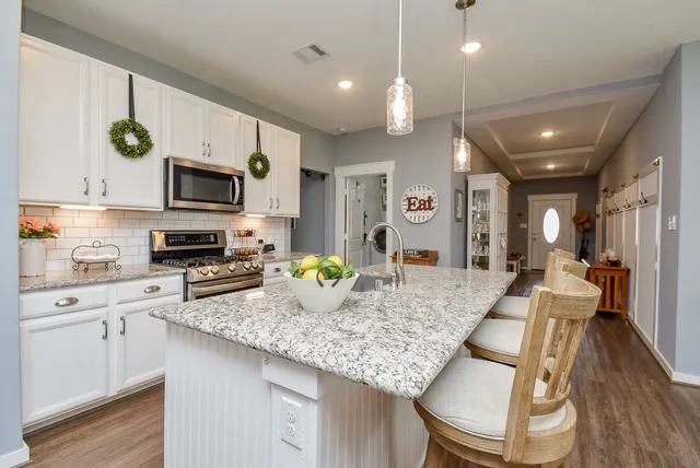 a kitchen with stainless steel appliances kitchen island granite countertop a dining table chairs and sink