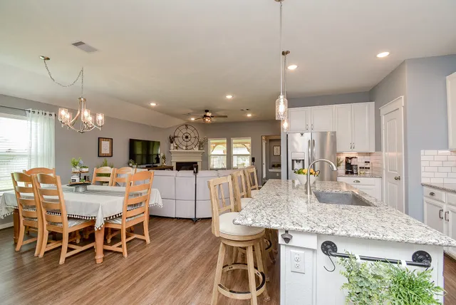 a kitchen with stainless steel appliances granite countertop a stove top oven a sink dishwasher a dining table and chairs with wooden floor