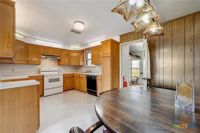 a kitchen with stainless steel appliances a stove top oven a sink dishwasher and a refrigerator with wooden floor