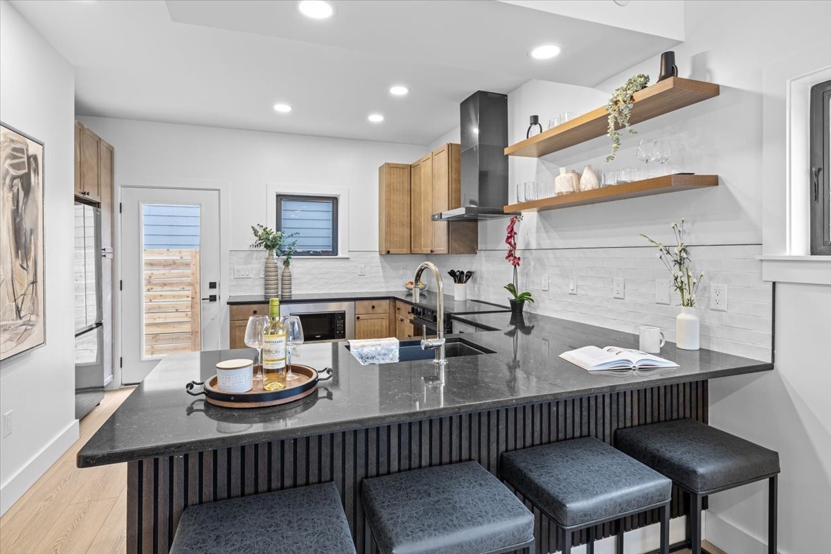 2406 West 10th Street, Unit A Austin, TX 78703 - Photo 3 of 13 a kitchen with stainless steel appliances kitchen island granite countertop a sink and chairs