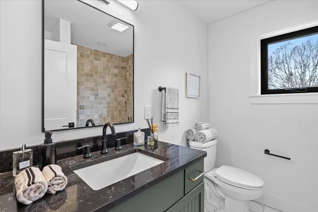 a bathroom with a granite countertop sink mirror and toilet