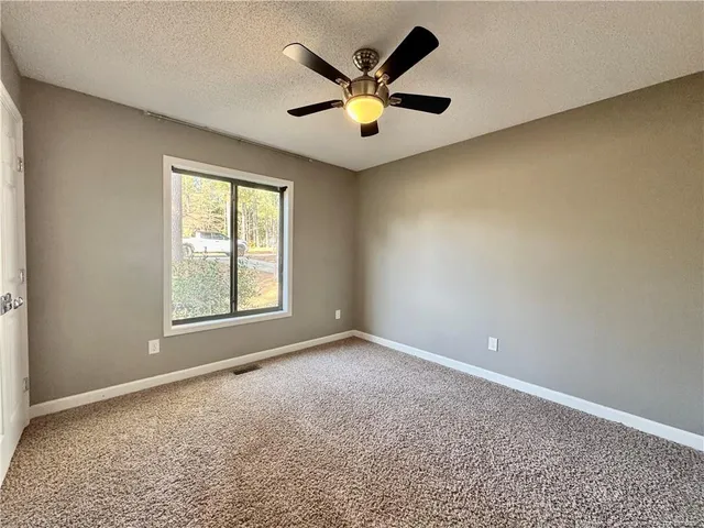 an empty room with ceiling fan and window