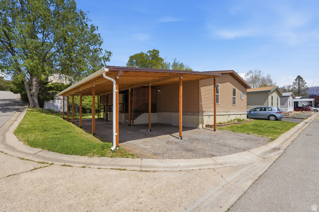 2875 North Hill Field Road, Unit 111 Layton, UT 84041 - Photo 22 of 30 View of side of property with a lawn, an attached carport, and driveway