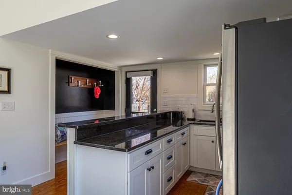 a kitchen with granite countertop white cabinets and black appliances