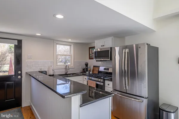 a kitchen with kitchen island granite countertop stainless steel appliances a sink stove refrigerator and a window