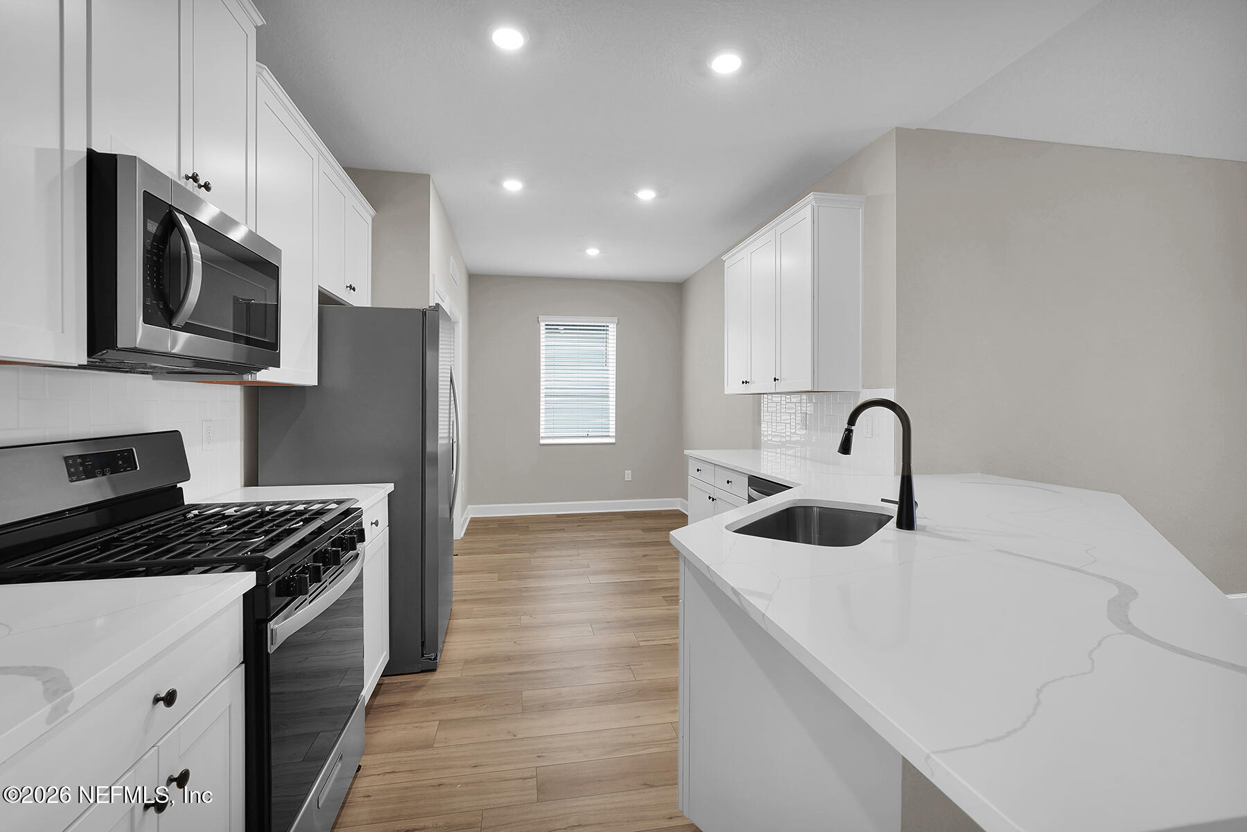 2420 Pemrose Loop Middleburg, FL 32068 - Photo 7 of 25 a kitchen with stainless steel appliances a sink a stove top oven a refrigerator with white cabinets and wooden floor