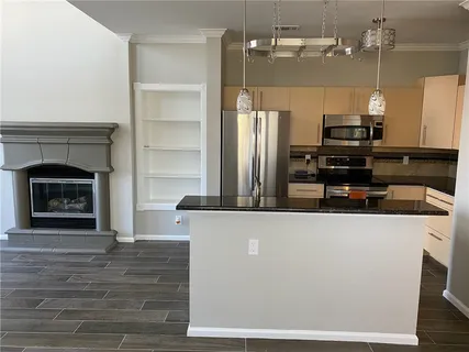 a living room with stainless steel appliances kitchen island a fireplace and a refrigerator