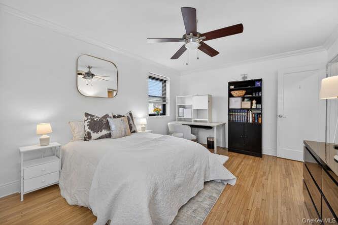 46 Terrace Circle, Unit 1B Great Neck, NY 11021 - Photo 6 of 16 a spacious bedroom with a bed and a chandelier