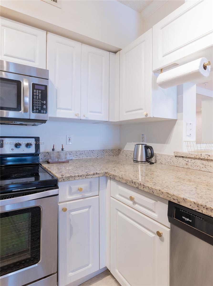17100 North Bay Road, Unit PH1912 Sunny Isles Beach, FL 33160 - Photo 11 of 39 a kitchen with granite countertop white cabinets and stainless steel appliances