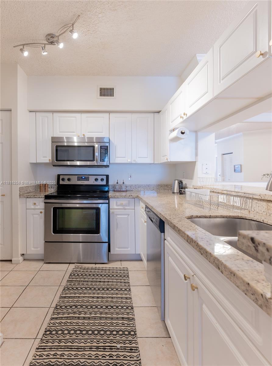 17100 North Bay Road, Unit PH1912 Sunny Isles Beach, FL 33160 - Photo 10 of 39 a kitchen with stainless steel appliances granite countertop a stove a sink and a microwave
