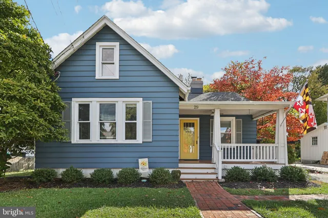 a view of a brick house with a yard plants and large tree