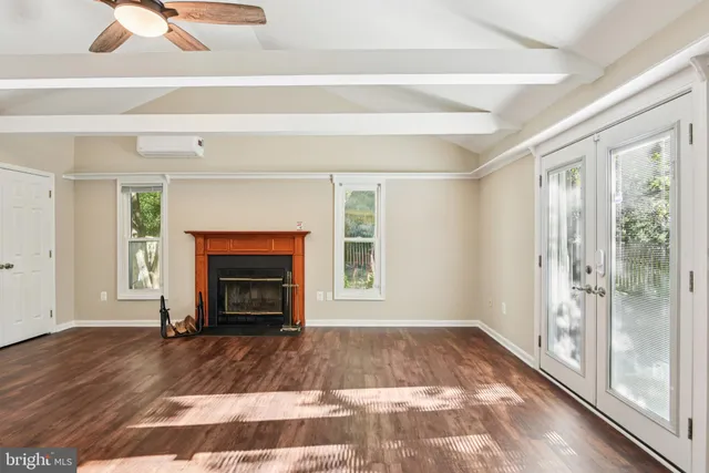 a view of an empty room with wooden floor fireplace and a window