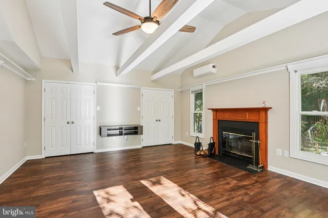 an empty room with windows fireplace and wooden floor