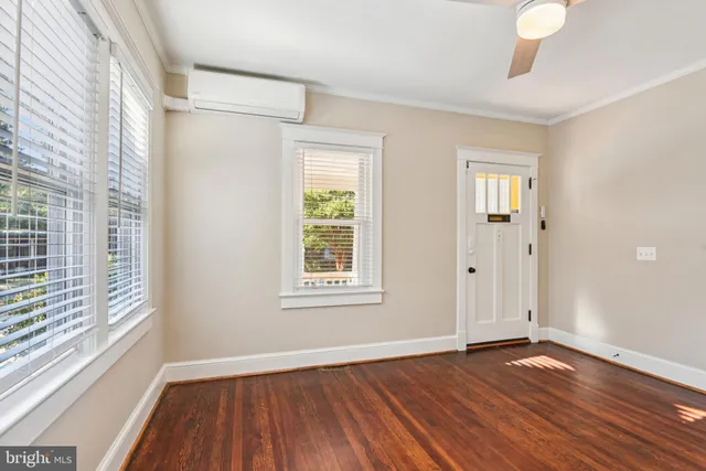 a view of an empty room with wooden floor and a window