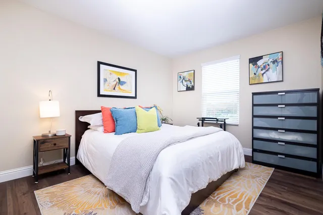 a bedroom with a bed and a lamp on dresser