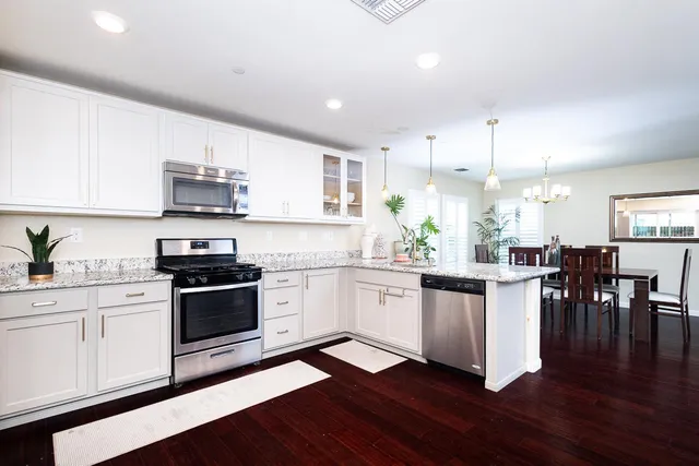 a kitchen with stainless steel appliances a white wooden cabinets and stove top oven
