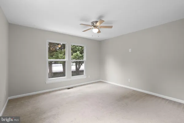 an empty room with windows and ceiling fan